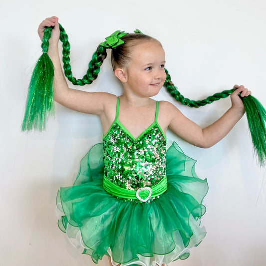 Young girl in a green sequined dance costume with long green braids against a white background