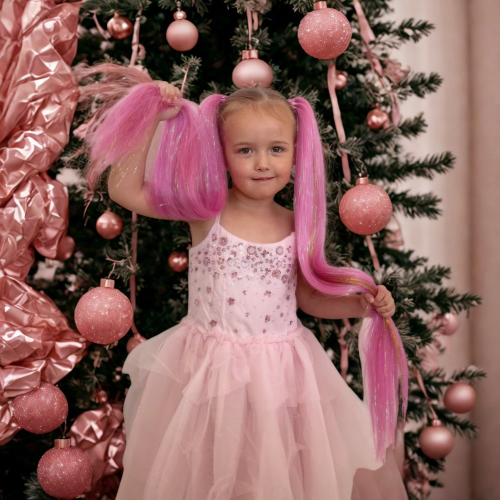 Child in a pink dress with long pink reusable mermaid pigtails