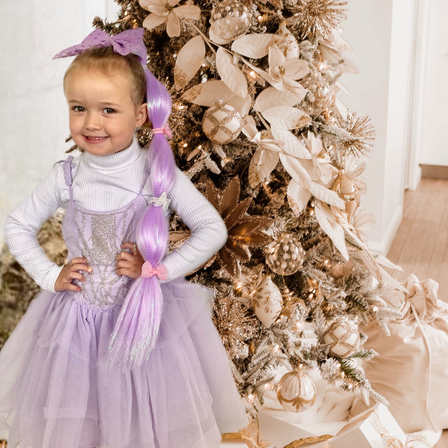 Young girl in a purple dress with matching lilac mermaid hair in front of Christmas tree